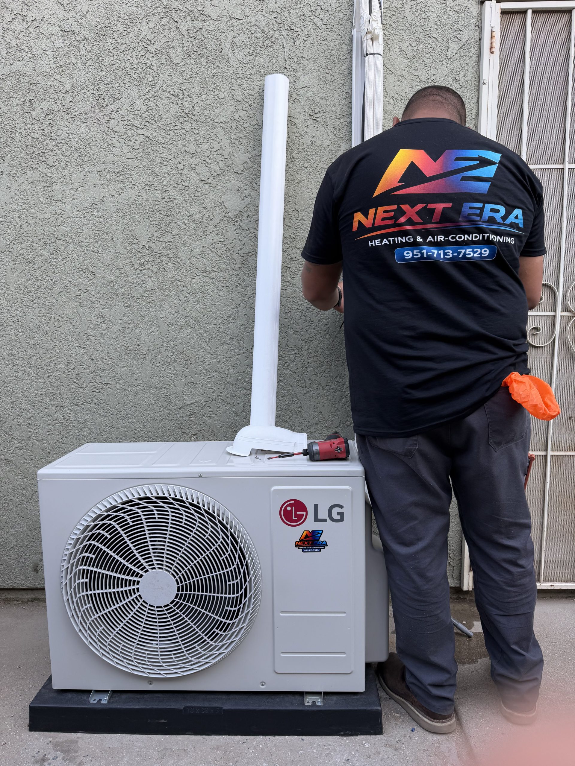 Next Era technician in branded gear installing an LG mini-split condenser unit